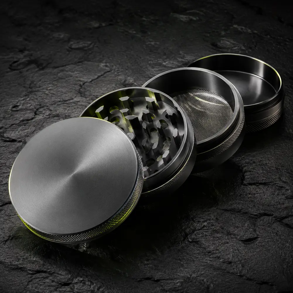 Open four-piece metal grinder photographed in a dark studio